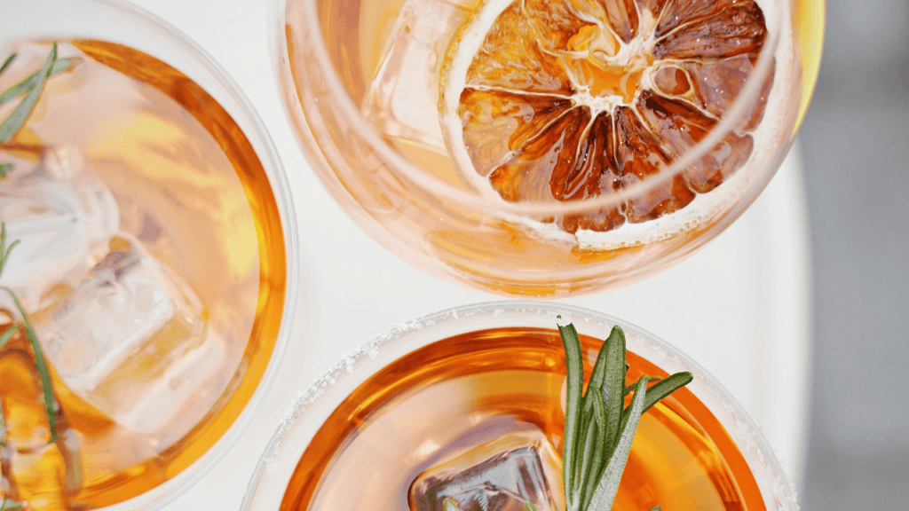 Aperitif-Cocktails mit Eiswürfeln, Rosmarin und getrockneter Orangenscheibe in stilvollen Gläsern