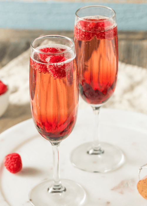 Zwei Gläser Himbeer-Sekt mit frischen Himbeeren als fruchtiger Aperitif