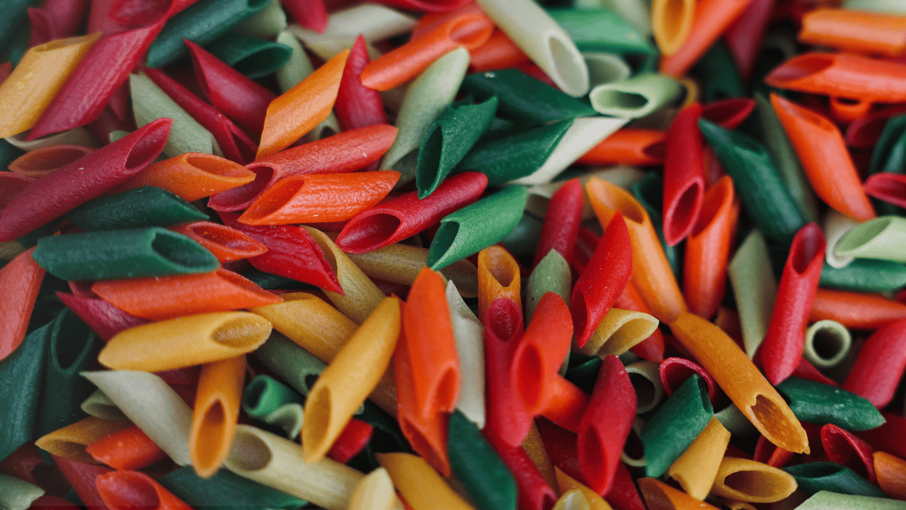 Bunte Penne-Nudeln in Rot, Grün, Orange und Gelb als Hintergrund für italienische Pasta