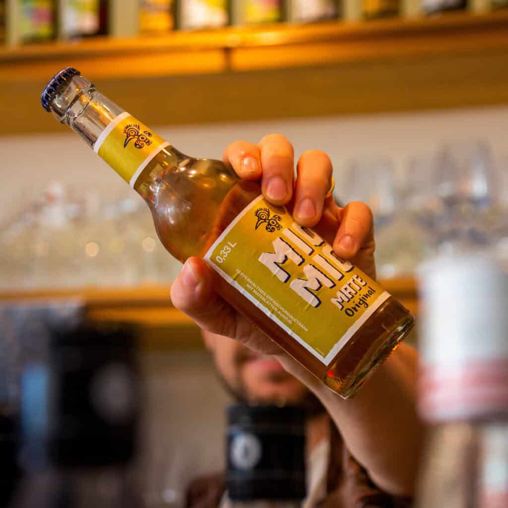 Mio Mio Mate Original in Glasflasche wird in einer Bar von Hand präsentiert
