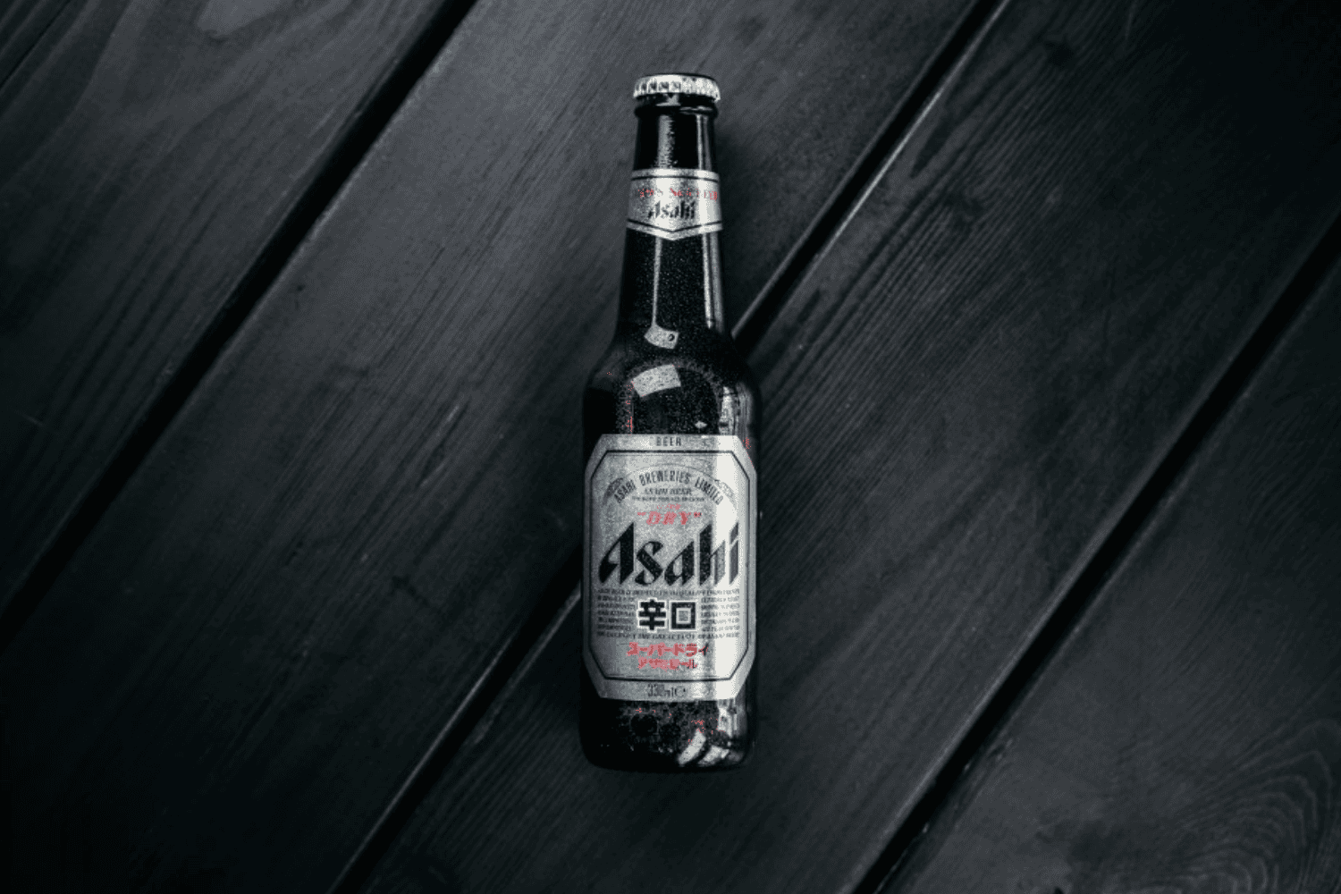 Asahi Super Dry Bierflasche auf dunkler Holzoberfläche