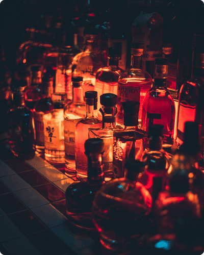 Auswahl verschiedener Spirituosenflaschen auf einer Bar bei stimmungsvoller roter Beleuchtung