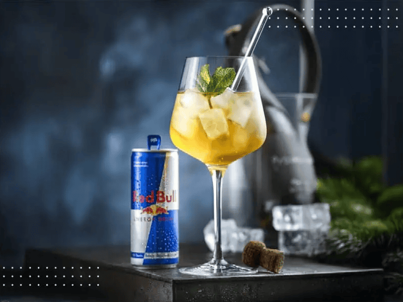 Red Bull Cocktail mit Eiswürfeln und Minze neben einer Red Bull Dose