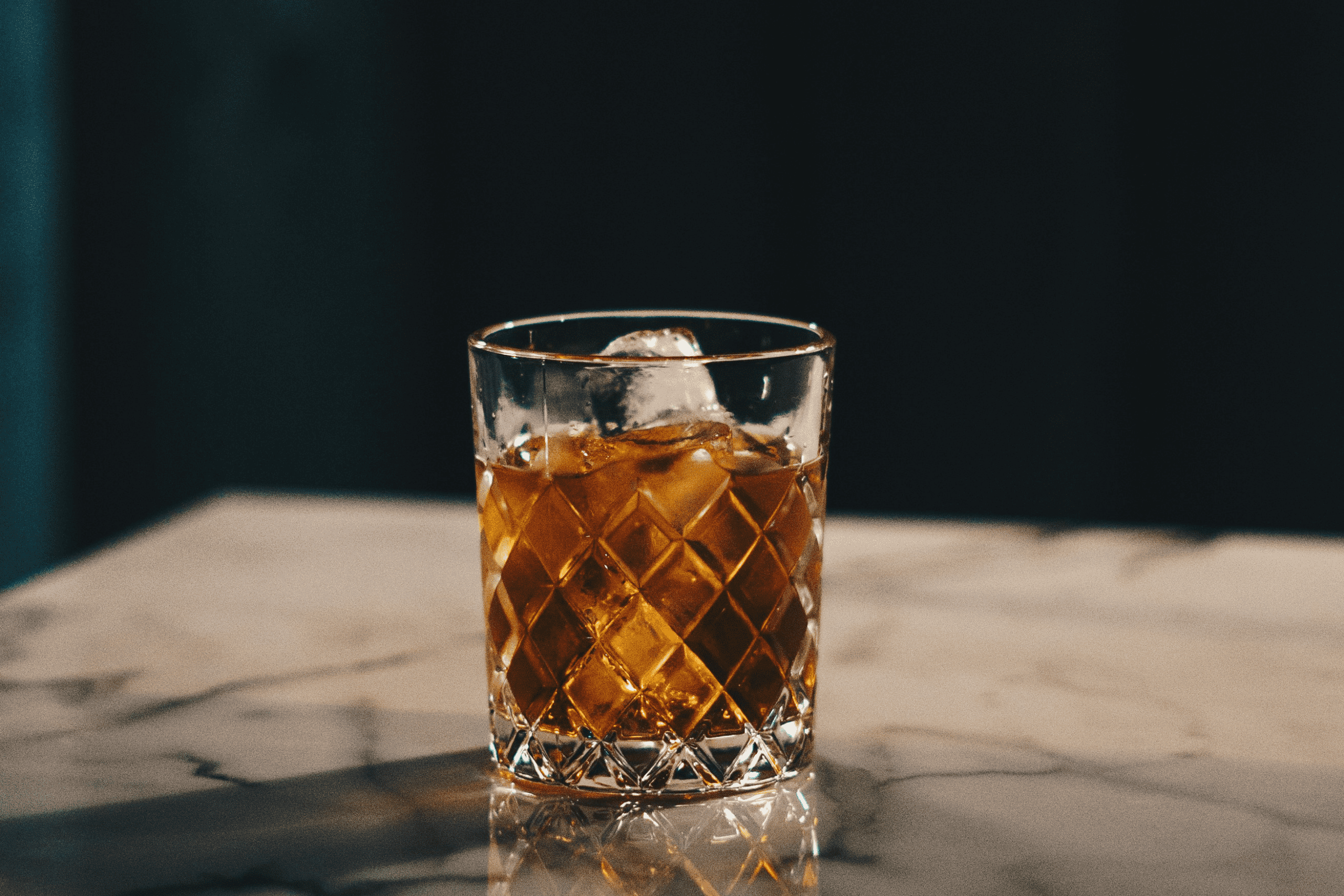 Whisky mit Eis im Tumbler Whisky mit Eis im geschliffenen Tumbler auf einem Marmortisch