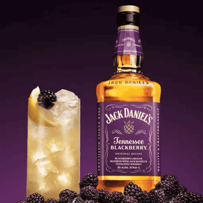 Jack Daniel's Tennessee Blackberry neben einem Longdrink mit Zitrone, Eiswürfeln und Brombeeren