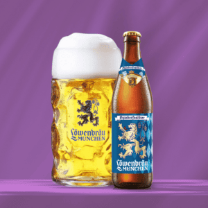 Löwenbräu Oktoberfestbier in Flasche und Bierglas vor violettem Hintergrund