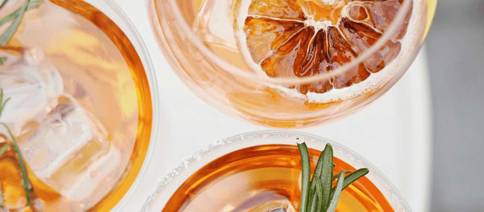 Aperitif-Cocktails mit Eiswürfeln, Rosmarin und getrockneter Orangenscheibe in stilvollen Gläsern