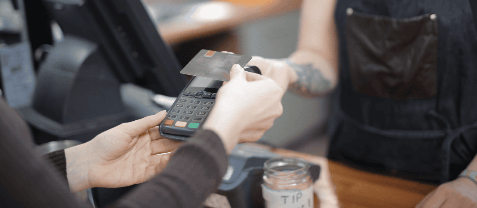 Person die eine Kreditkarte an ein Kartenlesegerät hält