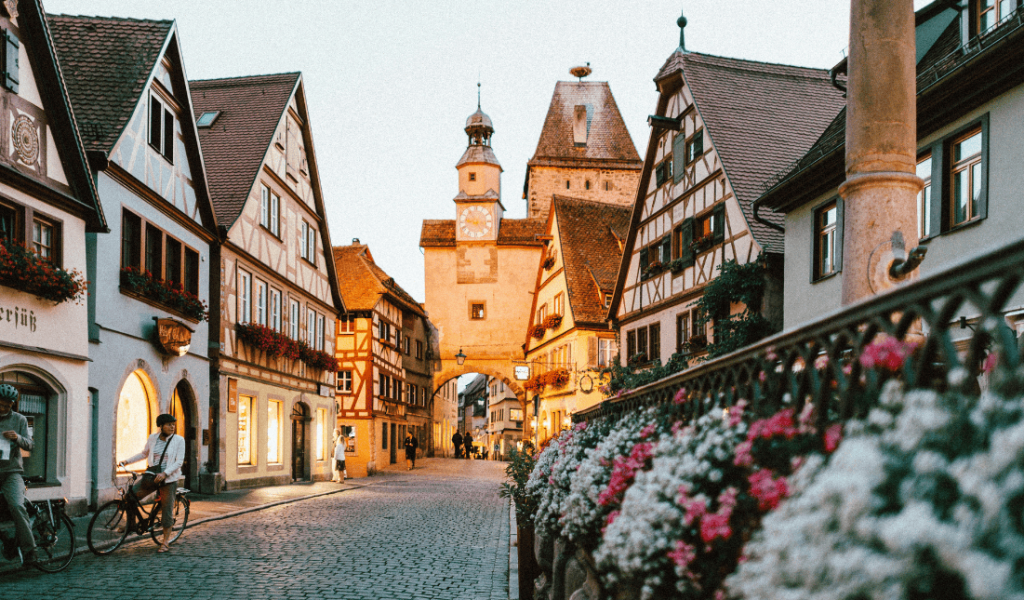 Übernachtungszahlen auf Rekordhoch Weiße und rosa Blütenblätter auf Metallzaun in der Nähe von Betonhäusern und Turm am Tag