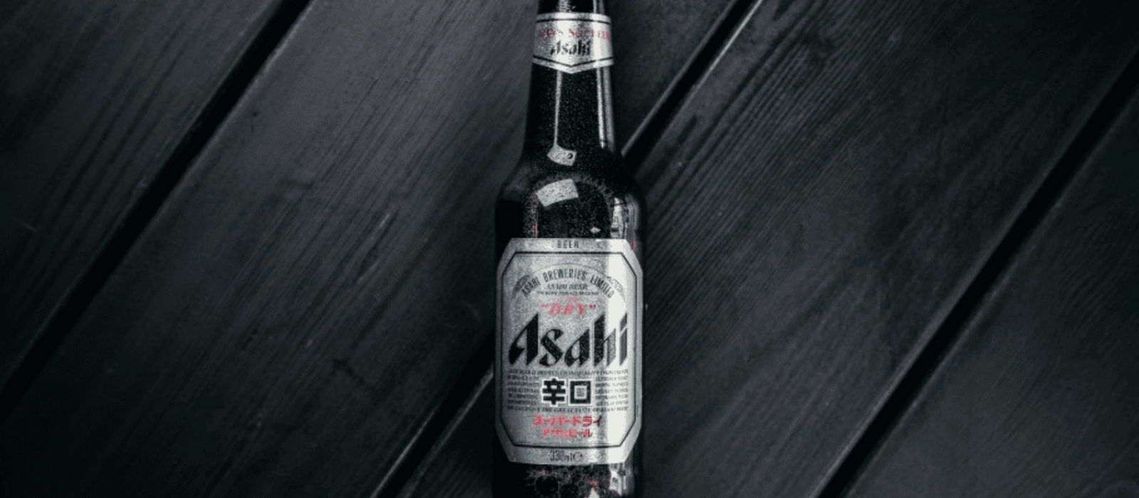 Asahi Super Dry Bierflasche auf dunkler Holzoberfläche