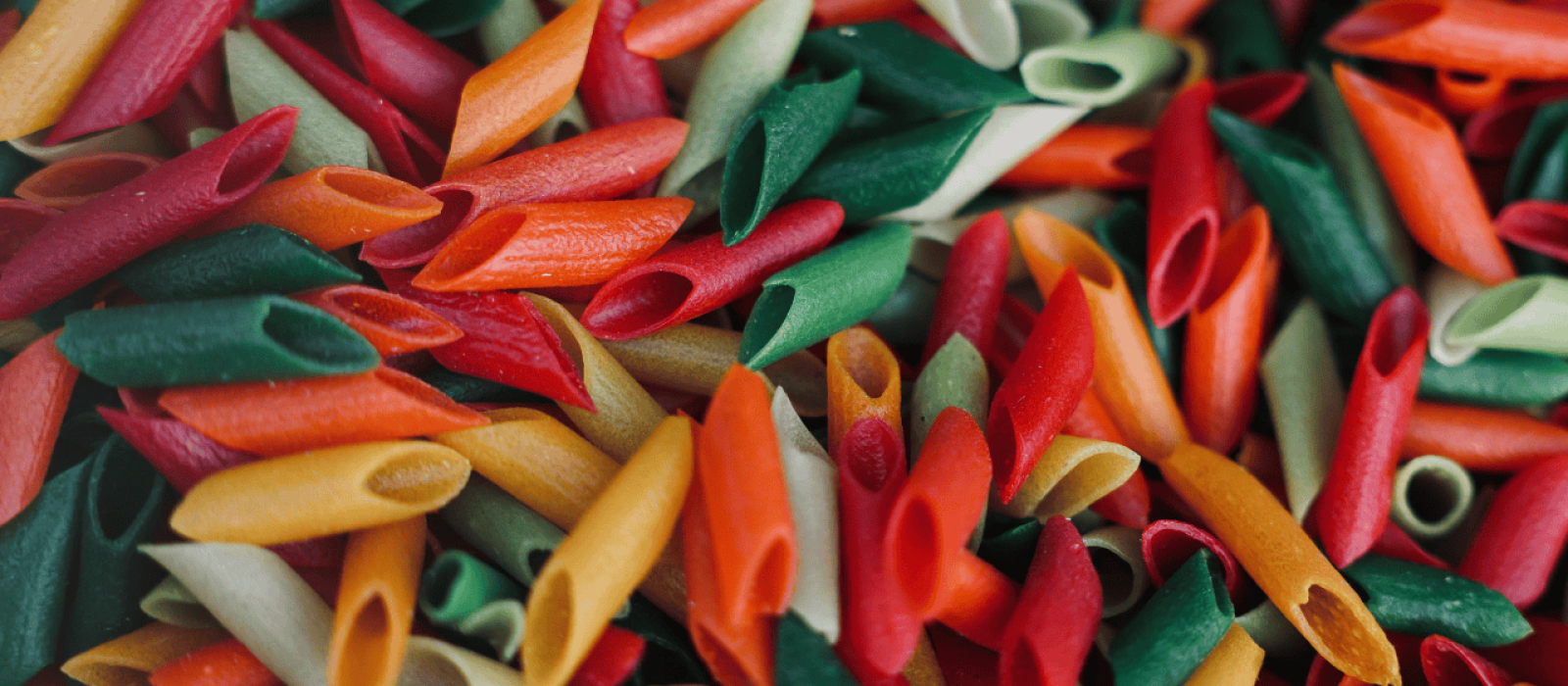 Bunte Penne-Nudeln in Rot, Grün, Orange und Gelb als Hintergrund für italienische Pasta