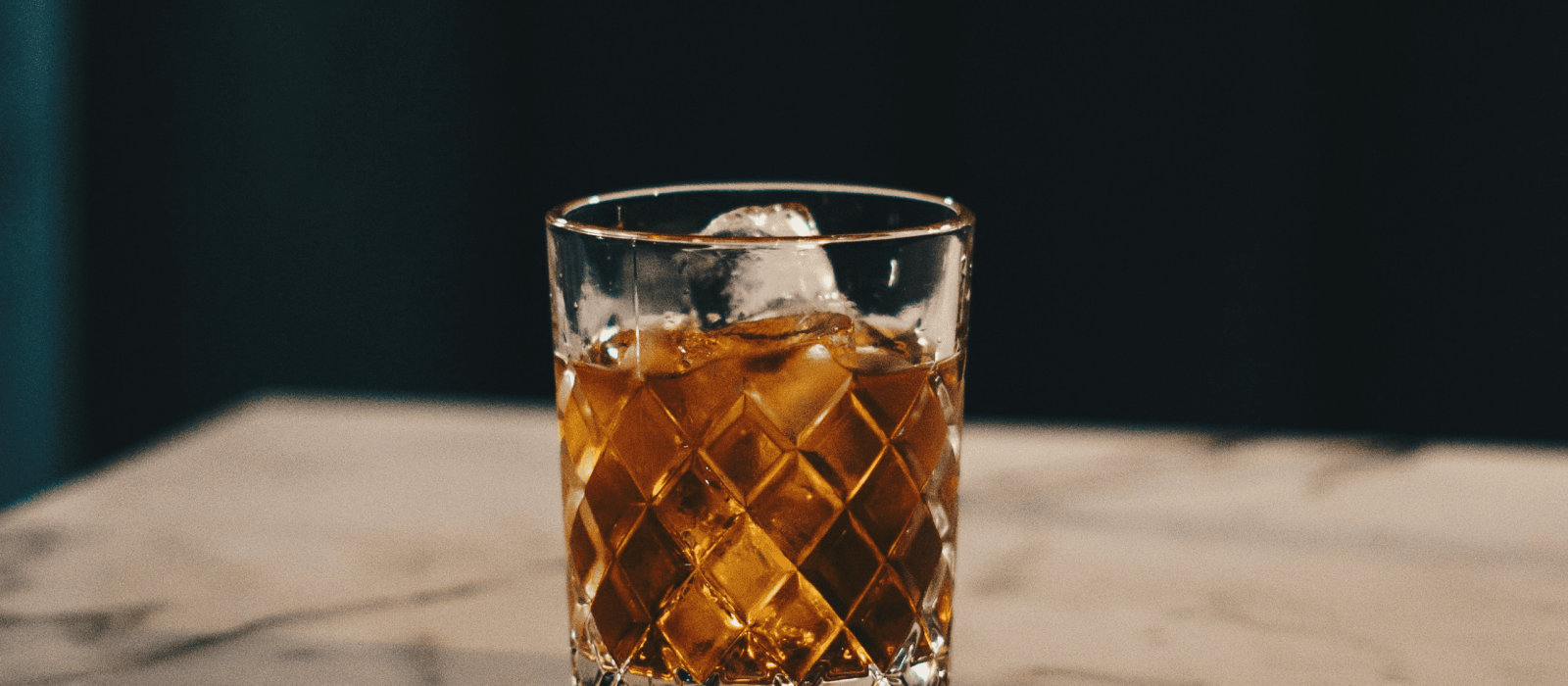 Whisky mit Eis im geschliffenen Tumbler auf einem Marmortisch